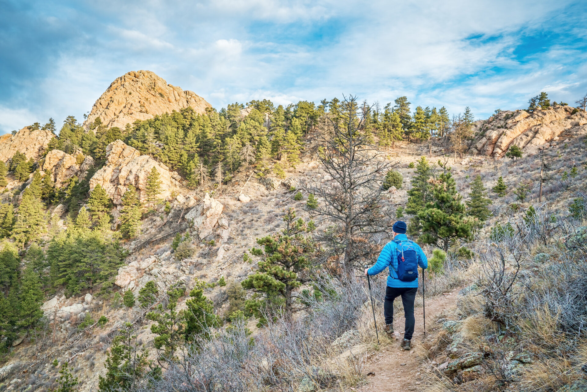 mail hiker with a backpack on a trail to Horsetooth Rock, a landmark of Fort Collins, Colorado, winter scenery without snow